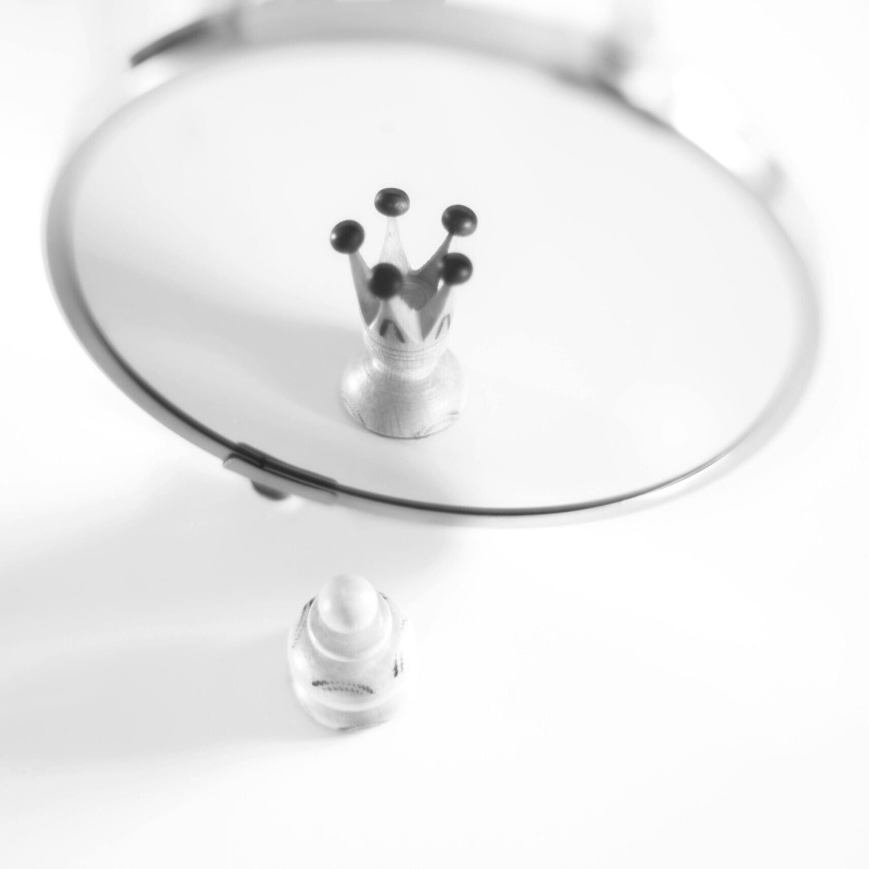 A pawn in front of a mirror is being reflected a king/queen