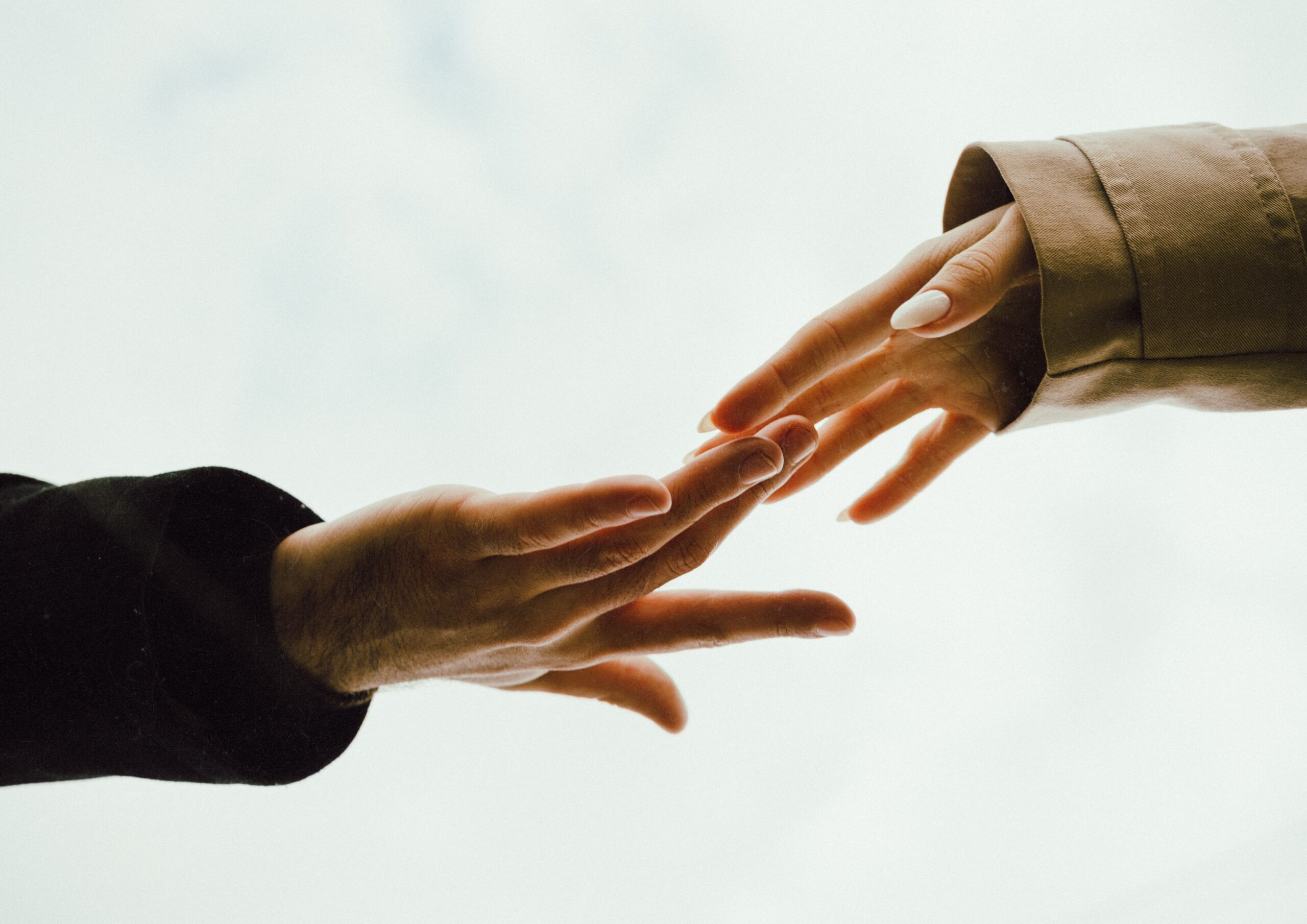 Two hands reaching out to each other, against a faint white backdrop